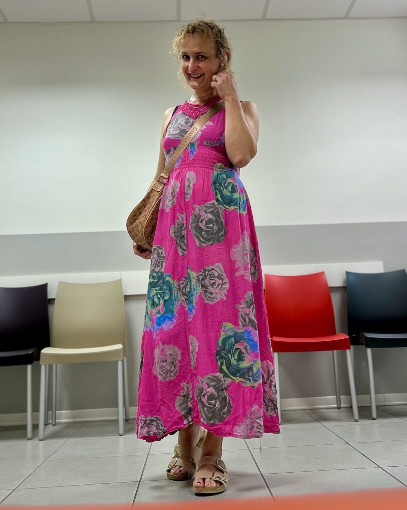 Bianca in piedi con vestito lungo a fiori, in sala d'attesa del medico di base